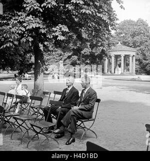 Zwei Männer sitzen im Kurpark am Elisabethenbrunnen hören und das Kurkonzert a Bad Homburg, Deutschland 1930er Jahre. Due uomini seduti vicino Elisabethenbrunnen bene e ascoltare il concerto di spa di Bad Homburg, Germania 1930s. Foto Stock