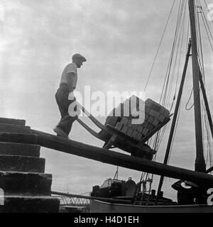 Ein Arbeiter am Rhein mit circuizione Schubkarre, Deutschland 1930er Jahre. Un lavoratore presso il fiume Reno con il suo barrow, Germania 1930s. Foto Stock