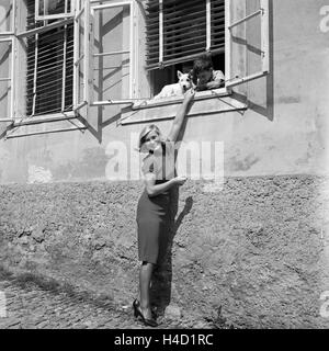 Eine junge Frau unterhält sich am Fenster Mit einem kleinen Jungen und seinem Hund, Deutschland 1930er Jahre. Una giovane donna con un ragazzo e il suo cane in una finestra, Germania 1930s. Foto Stock