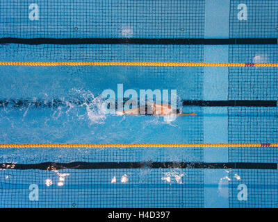 Vista superiore colpo di giovane uomo giri di nuoto in piscina. Nuotatore nuoto il crawl anteriore in una piscina. Foto Stock