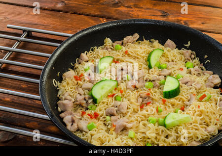 Tagliatelle cinesi con pollo in padella e tavolo in legno Foto Stock