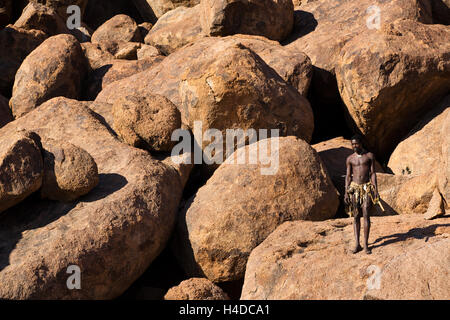 Il cacciatore africano dal popolo Damara rimane vicino alla baita di villaggio in Namibia, Sud Africa Foto Stock