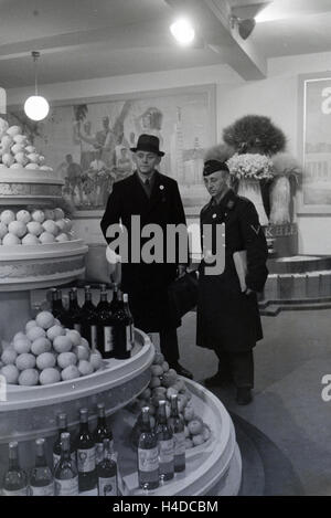 Besucher der Leipziger Frühjahrsmesse vor einem Messestand mit Spezialitäten südländischen, Deutschland 1941. I visitatori della Leipziger Frühjahrsmesse nella parte anteriore del piedistallo con delicatezza del Mediterraneo, Germania 1941. Foto Stock