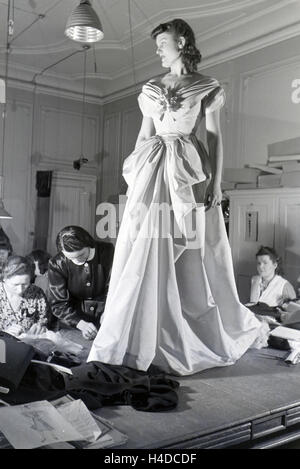 Ein modello und Schneiderinnen bei der Anprobe eines Kleides von Modeschpferin Annemaria Geise; Deutschland ca. 1939. Un modello di sarti e cercando un abito del designer di moda Annemaria Geise; Germania ca. 1939. Foto Stock