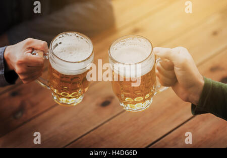 Stretta di mano con boccali da birra presso il bar o pub Foto Stock