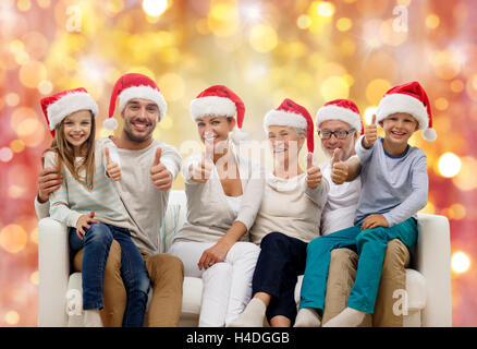 La famiglia felice in cappelli di Babbo Natale mostra pollice in alto Foto Stock