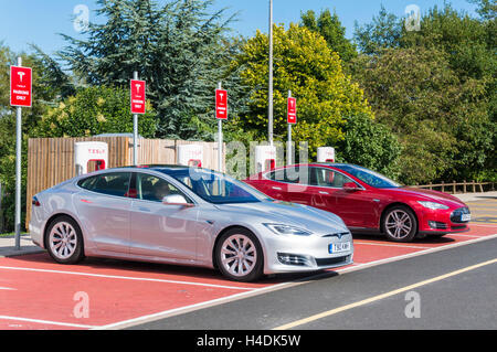 Auto elettriche Tesla Model S presso il punto di ricarica, Hopwood Service Station Birmingham UK GB Europe Electric Vehicle Foto Stock