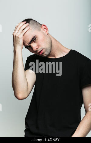 Uomo bello possing con la mano sulla testa Foto Stock