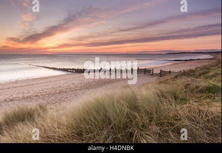 Blyth spiaggia dalla sabbia dunces sopra i pennelli in legno proteso verso il mare a sunrise Foto Stock