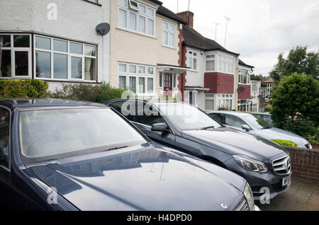 Auto parcheggiate su la trazione anteriore di case a Barnet, North London, England, Regno Unito Foto Stock