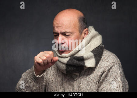 Uomo anziano è malato da raffreddore o polmonite. uomo anziano in un maglione e una sciarpa di lana fortemente tosse Foto Stock