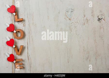 La parola amore con cuori rossi su sfondo bianco in legno antico Foto Stock