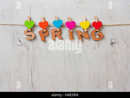 word spring and colored hearts on a white background old wooden Foto Stock