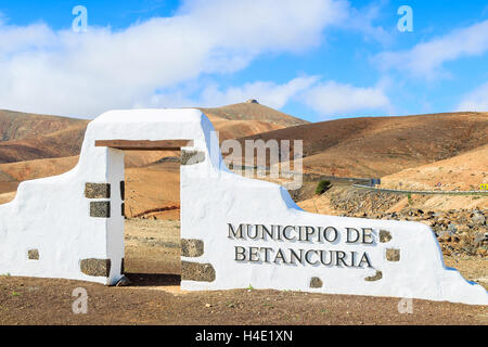 Tipico segno comune (bianco arch gate) vicino al villaggio di Betancuria con deserto paesaggio di montagna in background, Fuerteventura, Isole Canarie, Spagna Foto Stock