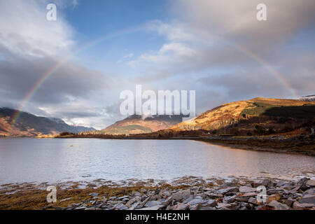 Rainbow oltre il Pap di Glencoe sulle rive di Loch Leven nelle Highlands scozzesi in inverno Foto Stock