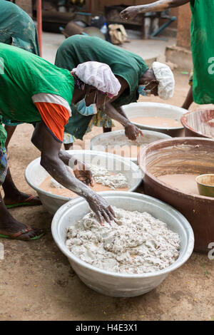 Il lavoro dei dipendenti di varianza manualmente il burro di karité a un commercio equo impianto di produzione in Réo, Burkina Faso. Foto Stock