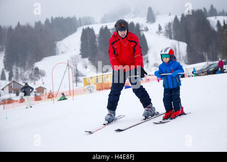 Happy little boy imparare a sciare con il suo padre durante le vacanze invernali nelle Alpi Svizzere Foto Stock