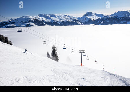 Piste da sci e seggiovia che conduce alla nebbia in Kitzbuhel ski resort, Alpi Tirolo, Austria Foto Stock