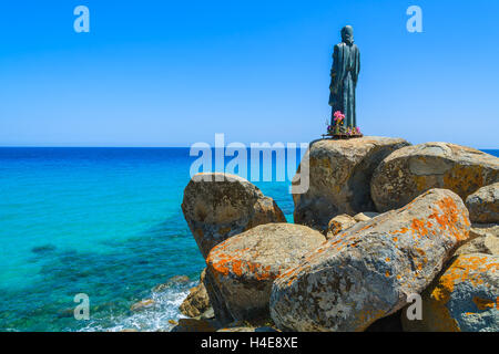 Gesù Cristo scultura su rocce di Cala Sinzias spiaggia e vista sul mare, l'isola di Sardegna, Italia Foto Stock