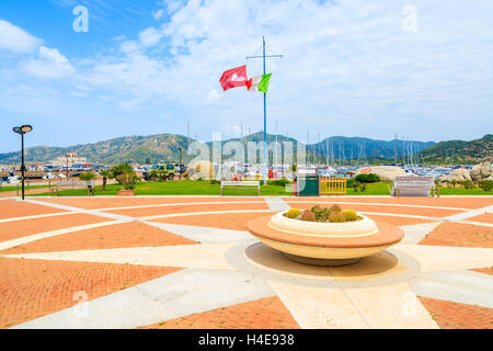 PORTO GIUNCO PORTO, SARDEGNA - 25 Maggio 2014: Piazza con vaso di fiori e bandiera italiana nel Porto Giunco porta. Questo luogo popolare per i turisti di noleggiare barche e fare gite intorno all'isola di Sardegna. Foto Stock