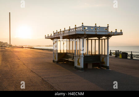 Ornati in regency posti a sedere un rifugio con panche in Brighton e Hove lungomare con sunrise in background Foto Stock