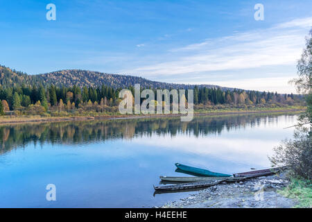 Bella giornata autunnale sul tranquillo fiume. Barche di legno ormeggiate alla banca del fiume. Bellissimo paesaggio fluviale. Foto Stock