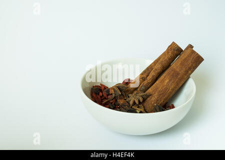 Cinese tradizionale le erbe essiccate in una ciotola bianco, utilizzato per la cottura Foto Stock