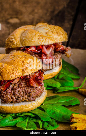 Bacon hamburger con patatine fritte di peperoncino e erbe frullato di banana sul tavolo di legno Foto Stock