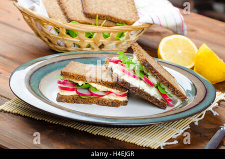 Snack sani - pane integrale con uovo-crema diffusione e verdure fresche foglie di rucola e ravanelli Foto Stock