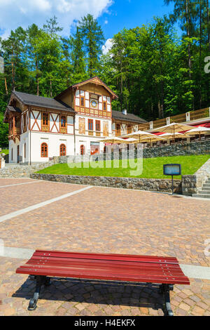 Banco in un parco con edifici storici nel centro storico della città di Szczawnica, Polonia Foto Stock