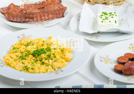 Una colazione abbondante con uova, pancetta, salsiccia e tostato baguette e cagliata fresca Foto Stock