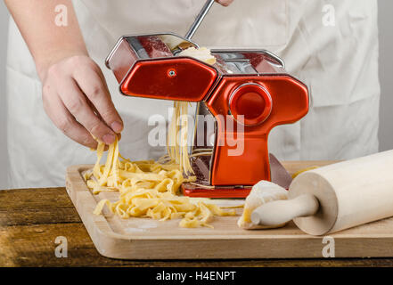 Lo Chef produzione pasta - La pasta italiana La cucina del macinino, wood board, mattarello, tutti realizzati da farina di semola Foto Stock