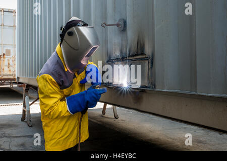 L'industria lavoratore con acciaio di saldatura per la riparazione di strutture di contenitore officina di fabbricazione nell'industria fabbrica. Foto Stock