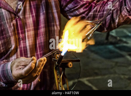 Glassblower all'opera in serata.Effetto della granella aggiunti in fase di post-produzione Foto Stock