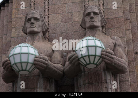 Progettato nel 1919 da notare architetto finlandese Eliel Saarinen, Hesinki massiccio di granito rail station ha una coppia di statue di sesso maschile. Foto Stock