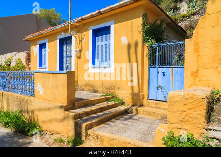 Giallo vecchia casa tipica con blu di Windows e persiane in Assos village, l'isola di Cefalonia, Grecia Foto Stock