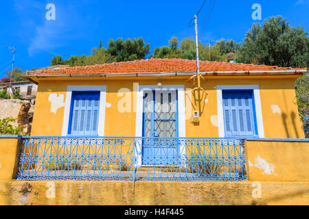 Giallo vecchia casa tipica con blu di Windows e persiane in Assos village, l'isola di Cefalonia, Grecia Foto Stock