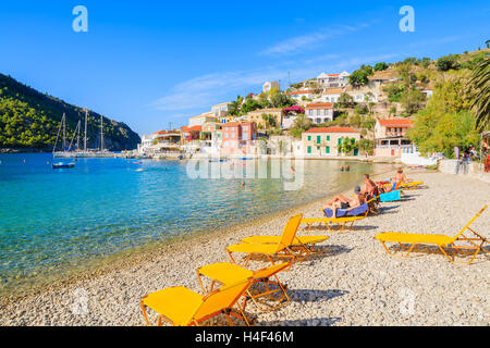 Giallo sdraio sulla bella spiaggia di Assos villaggio sull'isola di Cefalonia, Grecia Foto Stock