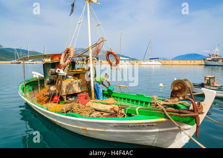 SAMI PORT, l'isola di Cefalonia, Grecia - Sep 20, 2014: pescatore pulisce greco tradizionale barca da pesca nel porto di Sami village. Barche colorate sono simbolo di isole greche. Foto Stock