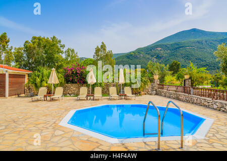 Una piccola piscina con lettini per prendere il sole nel paesaggio di montagna dell'isola di Kefalonia, Grecia Foto Stock