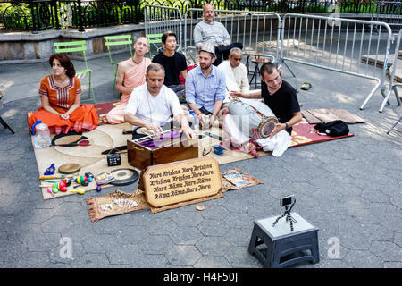 New York City,NY NYC Manhattan,Stuyvesant Square,parco pubblico,Hare Krishna,religione,culto,Asian adult,adults,man men maschio,woman female women,sitting on Foto Stock