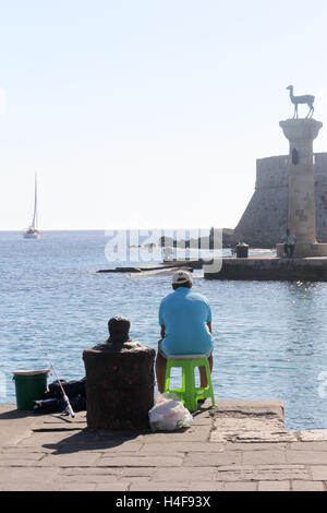 L'uomo la pesca nel porto di Mandraki, Rodi, Grecia Foto Stock