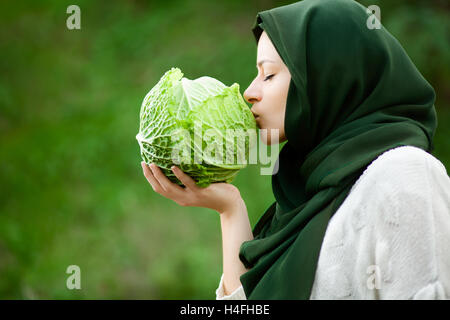 Vegano musulmano donna con velo baciando un cavolo verza Foto Stock