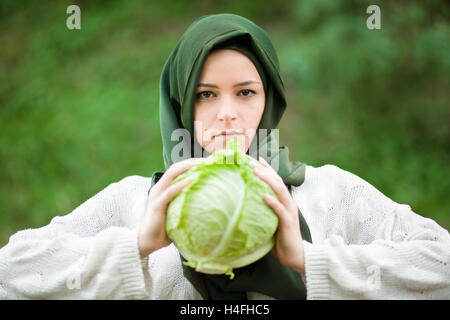 Vegano musulmano donna con velo tenendo un cavolo verza Foto Stock