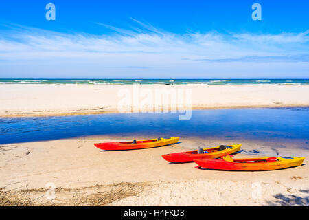 Canoe sulla spiaggia di sabbia bianca di Debki borgo dove il fiume Plasnica ha il suo estuario al Mar Baltico, Polonia Foto Stock