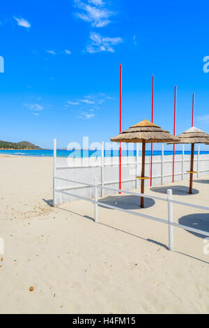 Lettini con ombrelloni su Villasimius spiaggia di sabbia bianca, l'isola di Sardegna, Italia Foto Stock