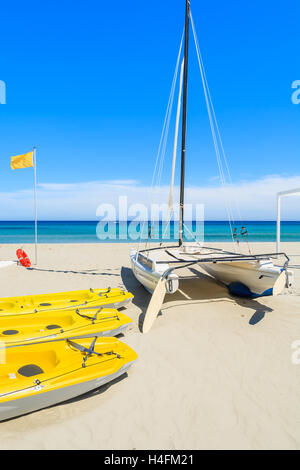 PORTO GIUNCO SPIAGGIA, SARDEGNA - 27 Maggio 2014: giallo kayak catamarano e barca sul Porto Giunco spiaggia, l'isola di Sardegna, Italia Foto Stock