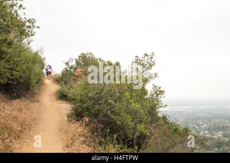 Gli escursionisti a piedi fino il sentiero su Bailey Canyon al di fuori di Los Angeles con la Sierra Madre in distanza Foto Stock