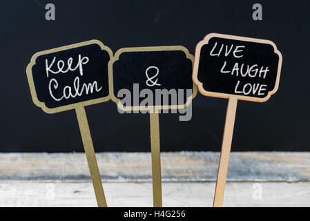 Mantenere la calma e a vivere ridere amore messaggio scritto con un gessetto su mini etichette di Blackboard Foto Stock