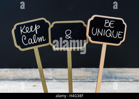 Mantenere la calma e di essere unico messaggio scritto con il gesso sulla mini etichette di Blackboard Foto Stock